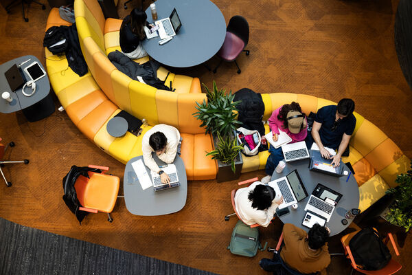 Northeastern students doing computer work on yellow seats